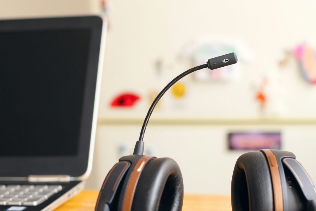 A headset sitting on a desk with a computer in an office representing a business exploring the best contact center software.